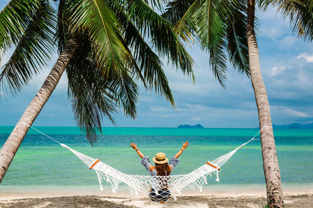 上,双臂举到头顶,两棵棕榈树之间,在一个热带岛屿的海边,旅行暑假照片
