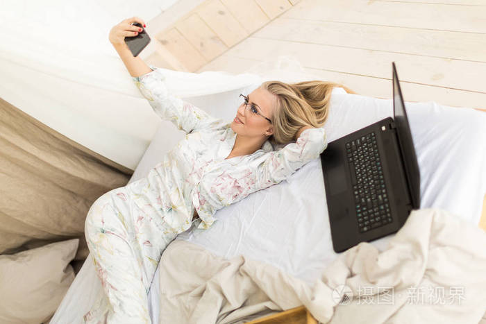 女人在床上用笔记本电脑自拍