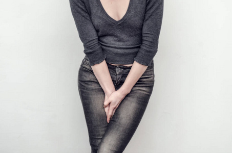 穿着牛仔裤的苗条女孩双手夹在两腿之间.w照片