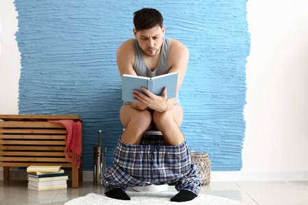 男人坐在家里的马桶上看书照片