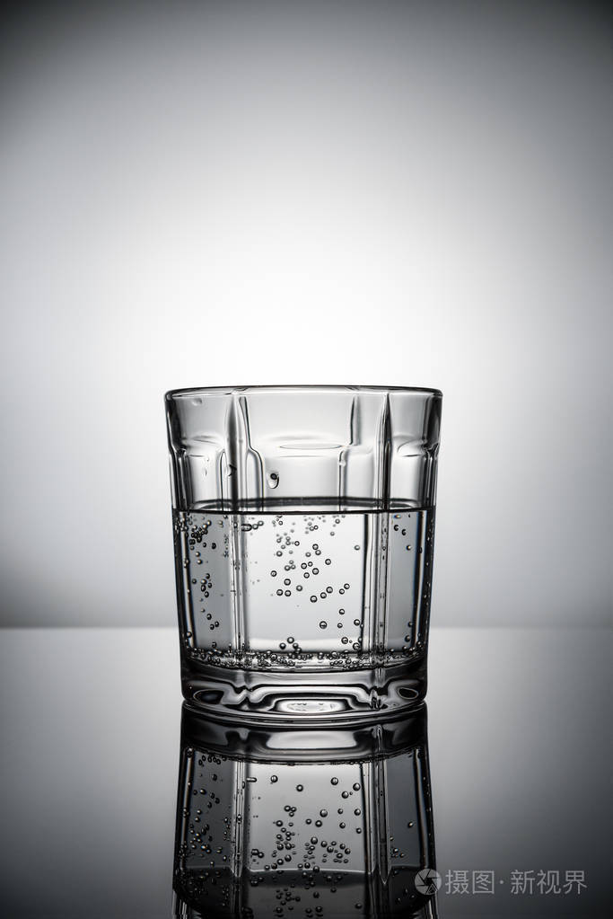 灰色背景上有气泡的一杯水