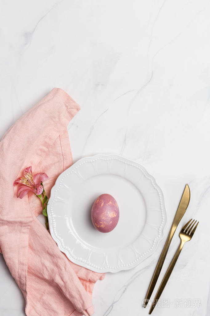 复活节餐盘白色盘子上的复活节粉红蛋大理石背景上有餐具和粉红色餐巾
