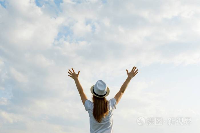 戴帽子的小女孩举手背影背景是蓝天白云地方为文字复制空间