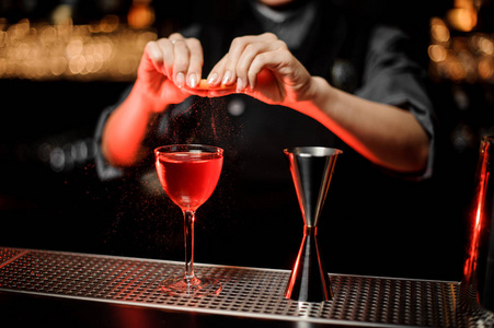 专业的调酒师女孩在美味的红色鸡尾酒中加入柠檬的味道照片