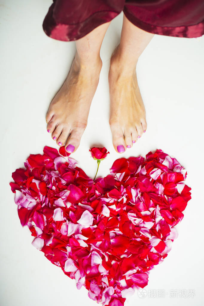 爱心在脚下用女性的腿和玫瑰花瓣做成的美丽的心形在温泉浴场或浪漫的