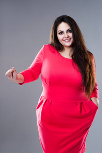 快乐的黑发大码模特,灰色背景的长发胖女人,身材积极照片