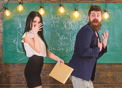 女学生拿着书拍着老师的屁股.笑脸上的女孩一边玩一边惩罚老师.