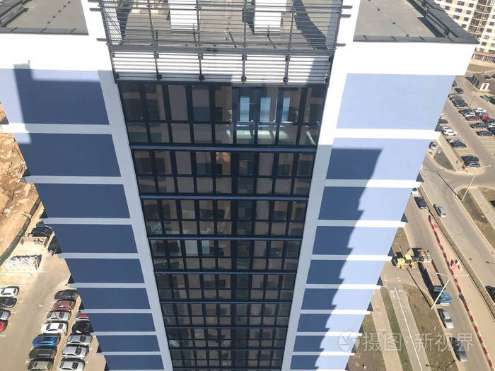 从一栋高大的摩天大楼屋顶的高处俯瞰庭院上有汽车对面是新大楼的另一