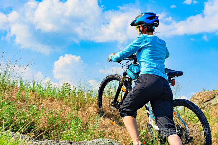 骑自行车的妇女推着自行车上陡坡
