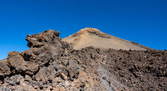 徒步旅行者徒步前往蓝天下的泰德火山口照片