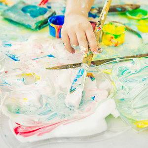 孩子的手拿着一把画笔,又蘸了蘸颜料照片