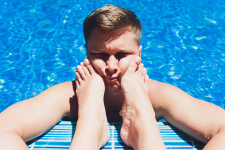 男人,女人的腿,游泳池,脚放在脸上,怕老婆的概念.照片
