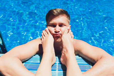 男人,女人的腿,游泳池,脚放在脸上,怕老婆的概念.照片