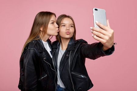 两姐妹双胞胎女孩摆造型,拍照自拍,穿着同样的白衬衫,不同发型的朋友