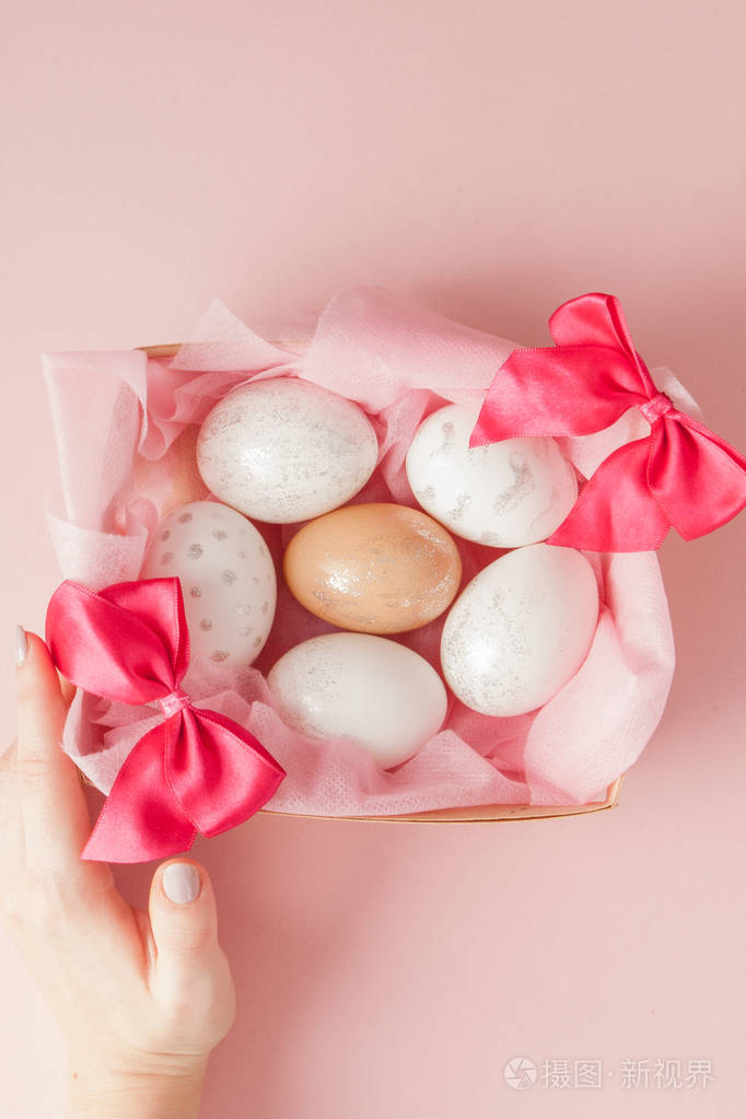 白色复活节彩蛋在粉红色背景的鸟巢里。在最小平面布局中设计柔和色调