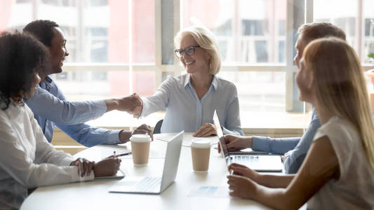 多元化的快乐商业伙伴在谈判后握手签合同照片