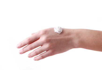 年轻漂亮的女人手上抹着奶油,隔离在白色上照片