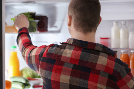 在家里从冰箱里拿食物的人图片