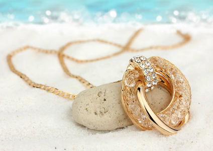 以沙滩上的金色珠宝吊坠为背景图片