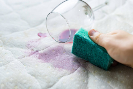 用海绵清洗酒渍.酒洒在白色床单上照片