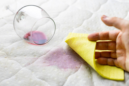 用海绵清洗酒渍.酒洒在白色床单上照片