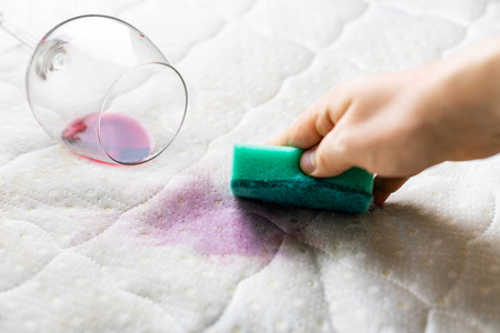 用海绵清洗酒渍.酒洒在白色床单上照片