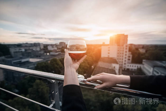 在夕阳的余晖中女人的手拿着酒杯
