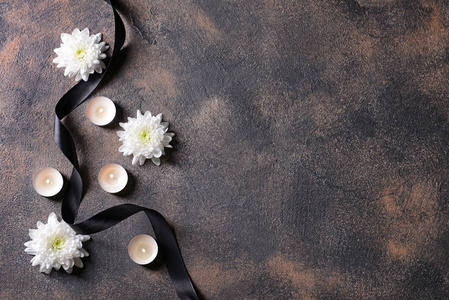 蜡烛哀悼黑色的哀悼丝带,鲜花和蜡烛在肮脏的背景上照片