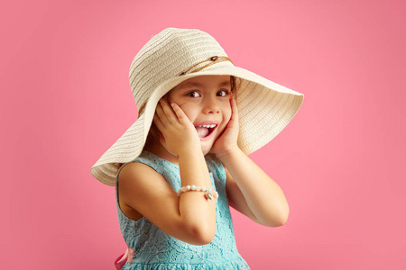 儿童嘴巴惊讶的小女孩戴着草帽,穿着蓝色连衣裙,双手贴在脸上,表示
