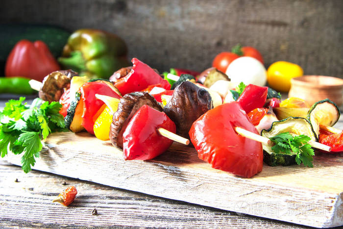 有机油炸蔬菜串,有茄子,辣椒,西葫芦,西红柿和洋葱,木板上有生菜和