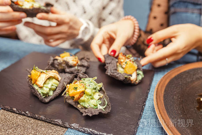 一名妇女在餐厅吃西班牙海鲜黑塔帕的特写镜头