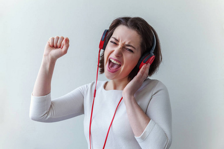 精力旺盛的年轻黑发女士戴着耳机听着音乐,在白色背景下独自唱歌照片