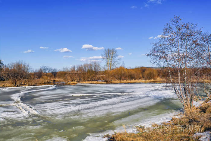 早春的景色融化了村庄边缘的一条小河上的冰