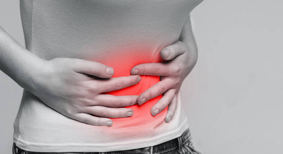 肚子抽筋白种人孕妇在背部疼痛灰色演播室背景上的白色内衣背部和腹部