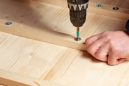 男性用螺丝刀将木块钉在木板上照片