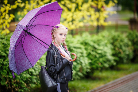 在雨中公园里撑伞的漂亮时髦小女孩的特写镜头照片