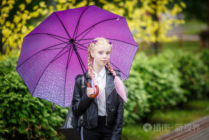 在雨中公园里撑伞的漂亮时髦小女孩的特写镜头