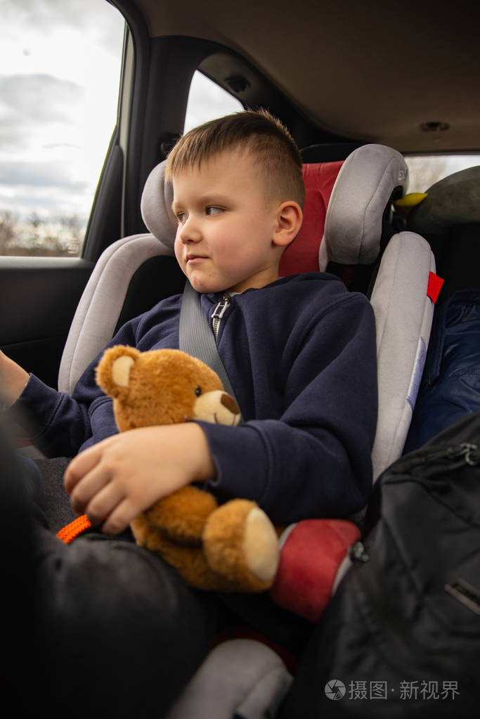 在旅途中可爱的小男孩和毛茸茸的小熊坐在后座上