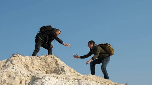 游客们互相握手,爬上山顶.一队男性旅行者走向胜利和成功.