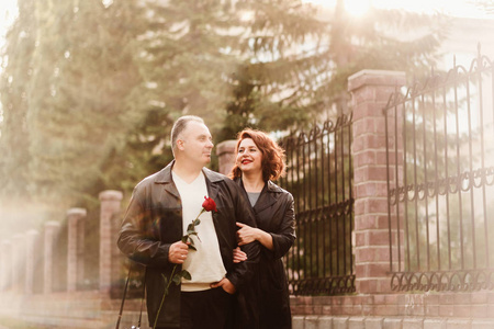 夏天,一对面带微笑的50岁男女在城市街道上携手同行照片