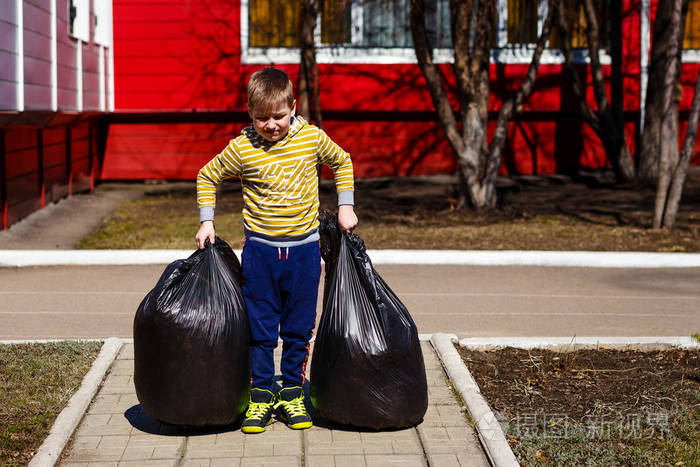 七岁男孩提着大塑料袋的垃圾