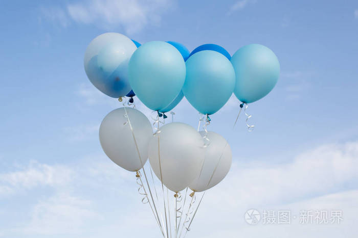 五颜六色的派对气球在蓝天的衬托下漂浮在半空中.