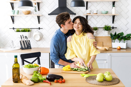 一位年轻女子在木制沙拉板上切新鲜蔬菜.烹饪.照片