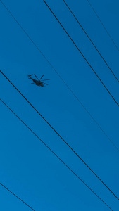 直升机在高压电线之间飞行图片