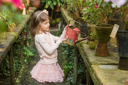 小女孩在温室里帮忙浇花和园艺照片