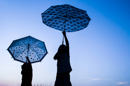 快乐的孩子们在公园的阳光下打着伞在大自然中剪影照片