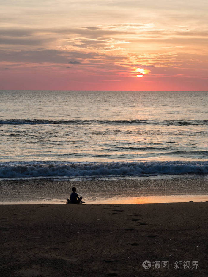 美丽的夕阳下一个不确定的人在沙滩上荷花姿势的剪影日落时冥想一个