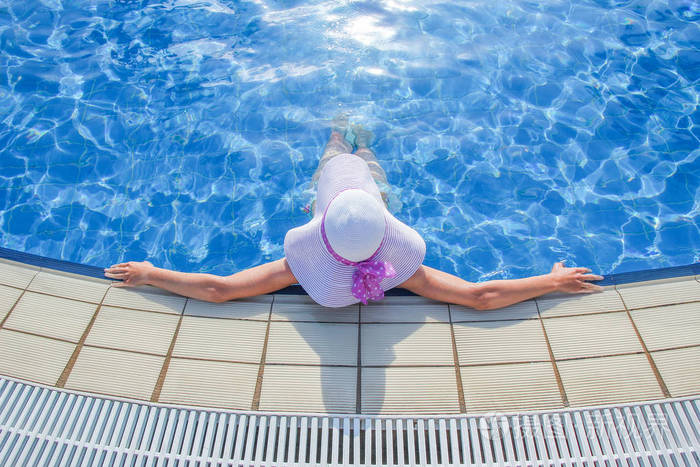 海边游泳池边戴帽子的快乐女孩