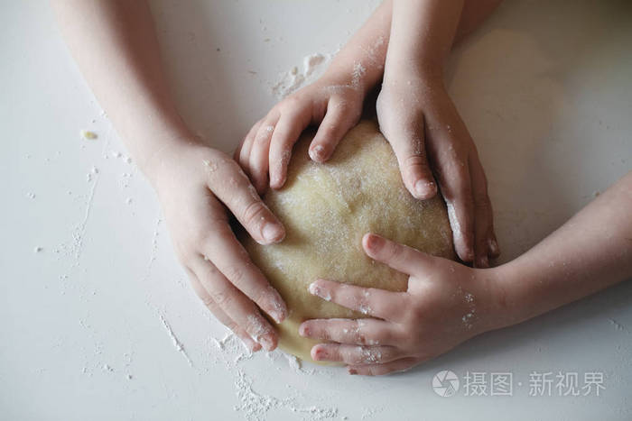 闭合四个孩子的手把面团压在白色的桌子上准备甜点