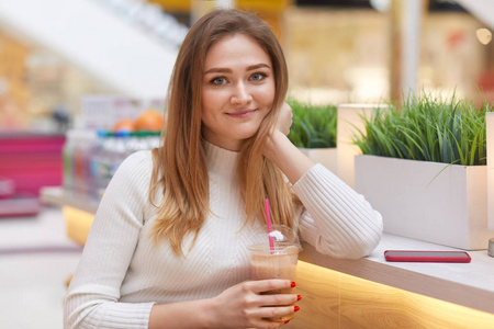 一个金发女人精神饱满,手里拿着鸡尾酒,穿着随意